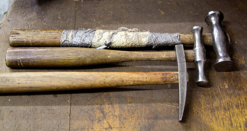 Trois marteaux à manche en bois sur un établi
